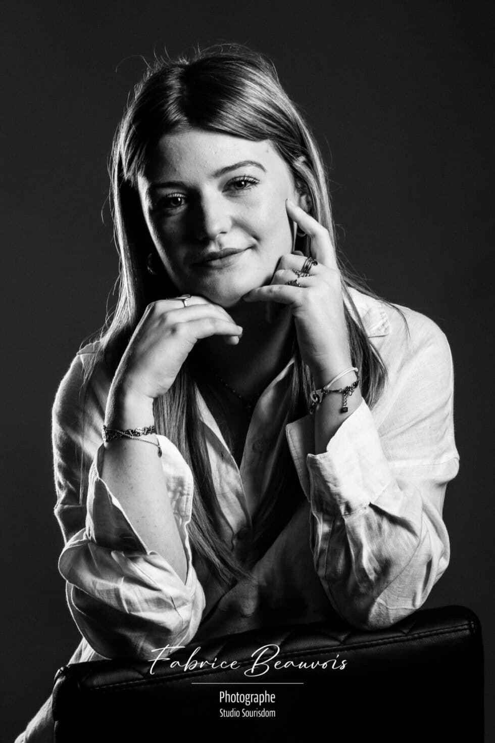Portrait de face dans une ambiance gris bleuté avec les mains positionnées sous le menton