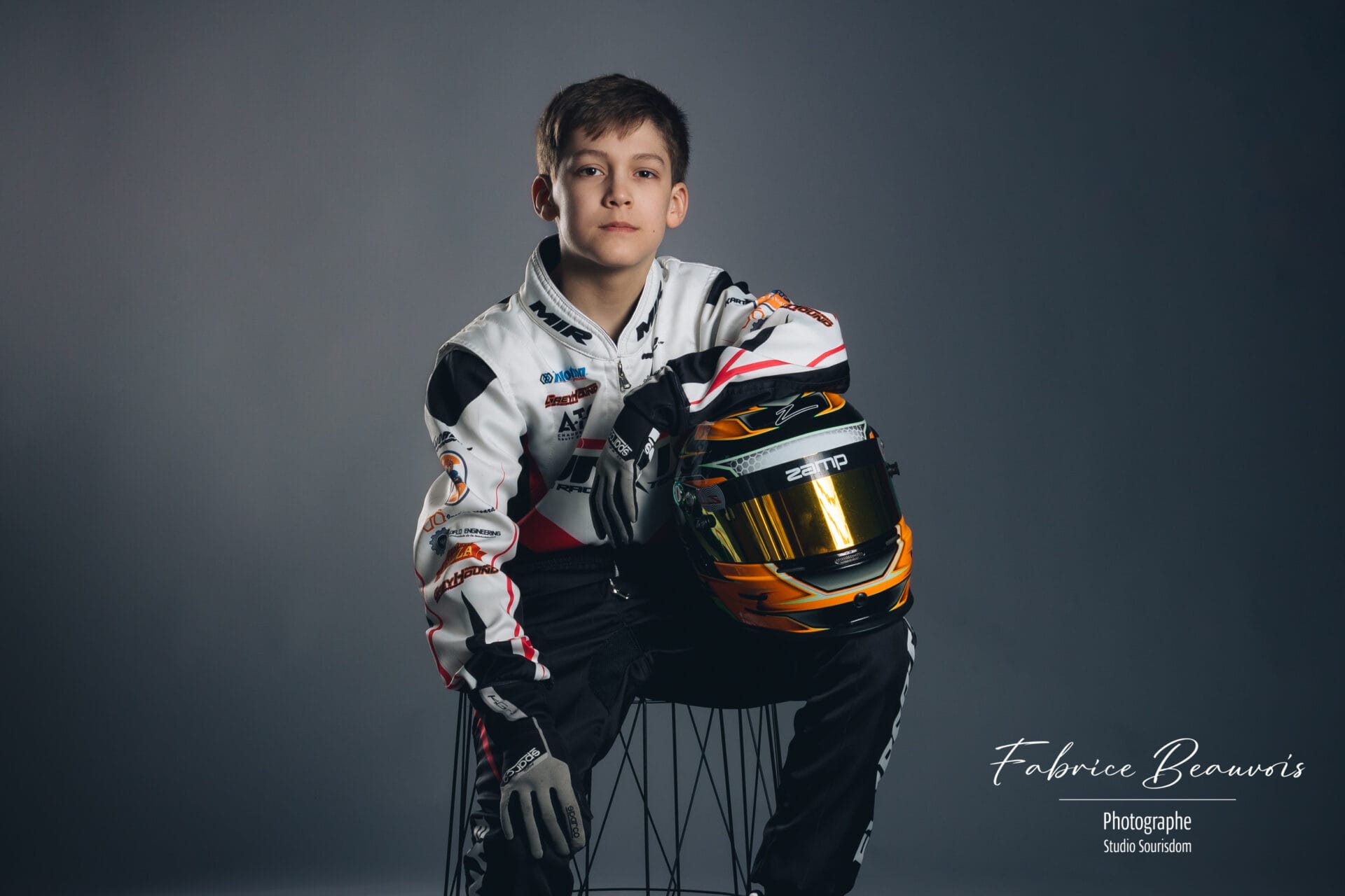 Portrait assis avec son bras sur le casque pour un champion de kart